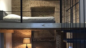 A loft-style bedroom with exposed wooden beams, a loft bed, a desk, and a chair. - H&B apartments Atoneli (Tbilisi)