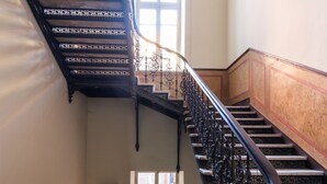 A grand staircase with ornate black railings and marble steps. - H&B apartments Atoneli (Tbilisi)