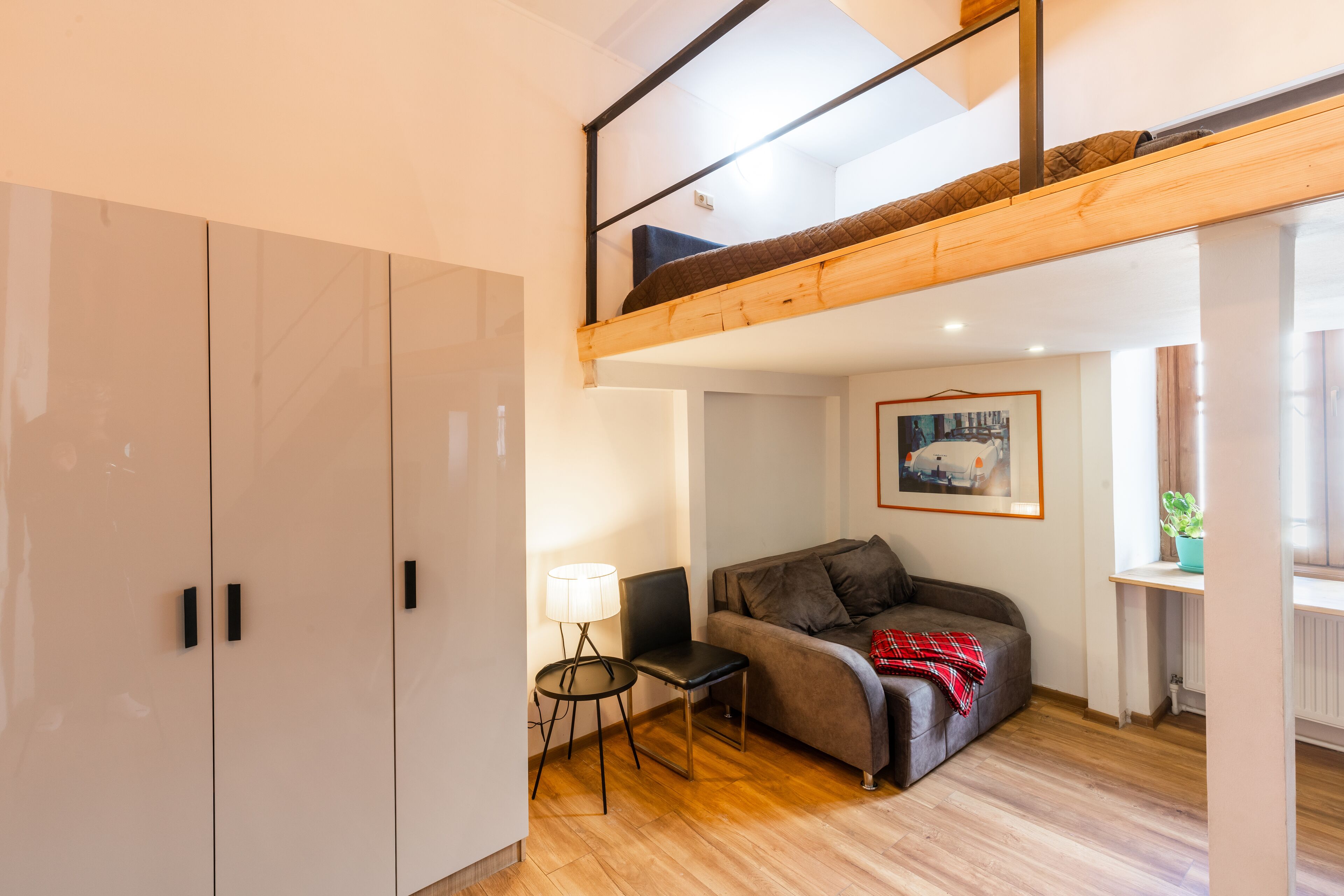 En kompakt bolig med køjeseng, sofa, lille bord og skab.