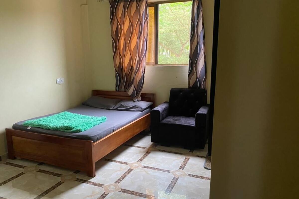 A bedroom with a bed, a chair, and a window with curtains.