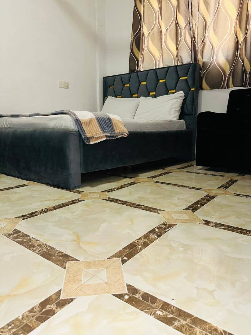 A bedroom with a bed, a headboard, and a patterned floor.