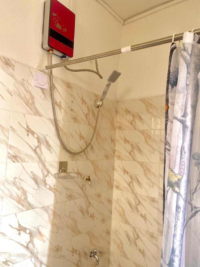 A bathroom with a shower, marble tiles, a towel rack, and a power outlet.