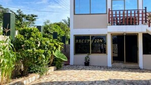 Un edificio con recepción, entrada empedrada y zonas verdes alrededor.