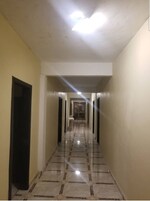 Um corredor comprido e estreito, com chão de azulejos e várias portas de cada lado.