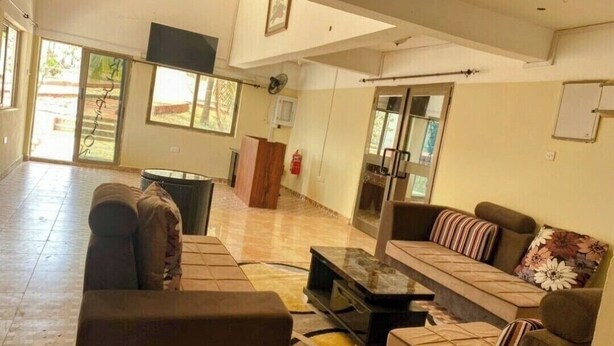 Un vestíbulo espacioso con un sofá, sillones y una mesa de centro. Se observa un extintor y una puerta que da al exterior.