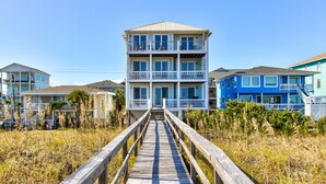 A multi-story building with a wooden walkway leading to it, surrounded by vegetation. - 🏖️Ocean Overlook-Beautiful 6BR Oceanfront Top 2 Floors of a Duplex🏖️ (Carolina Beach)