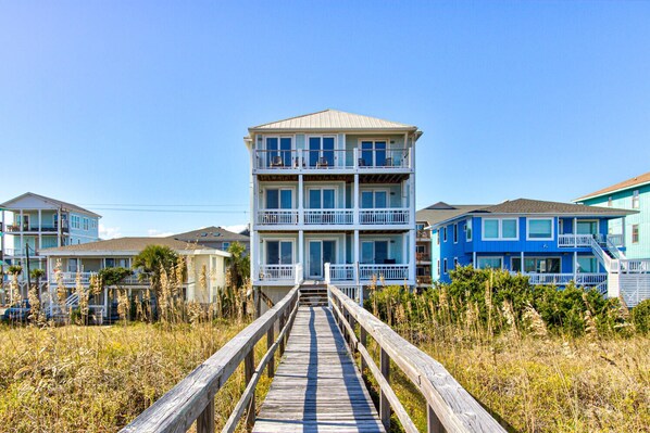 A multi-story building with a wooden walkway leading to it, surrounded by vegetation. - 🏖️Ocean Overlook-Beautiful 6BR Oceanfront Top 2 Floors of a Duplex🏖️ (Carolina Beach)