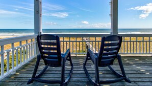 A wooden deck with two rocking chairs facing a beach view. - 🏖️Ocean Overlook-Beautiful 6BR Oceanfront Top 2 Floors of a Duplex🏖️ (Carolina Beach)