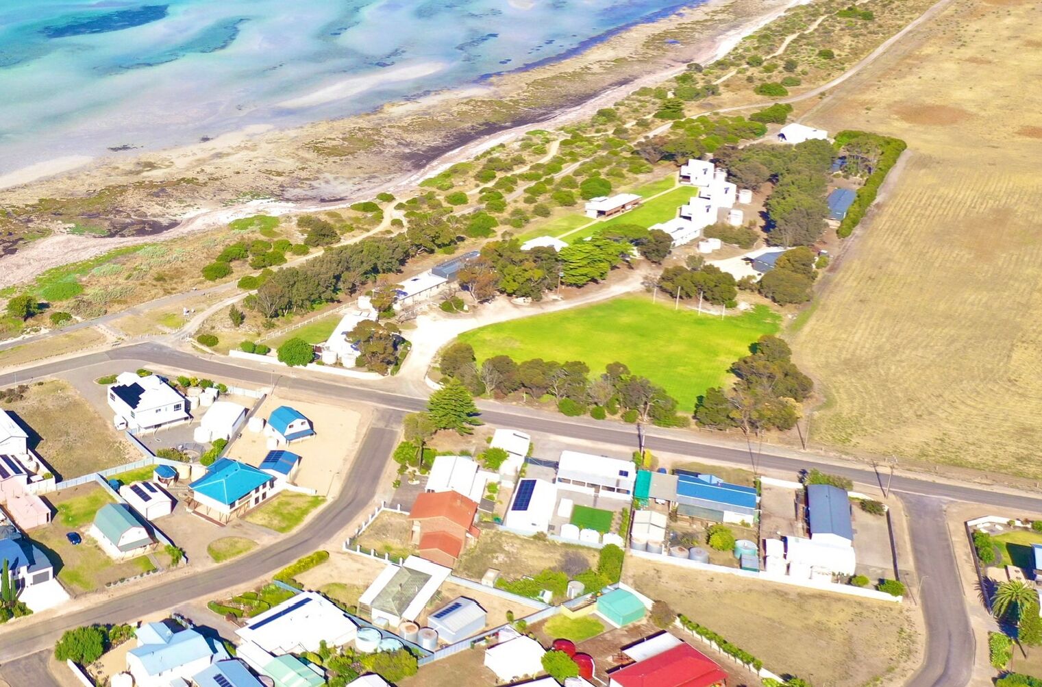 Vista aerea di una zona residenziale costiera con case, una strada e una spiaggia.