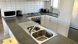 A modern kitchen with white cabinets, a stainless steel sink, a gas stove, and a window.