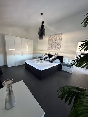 A modern bedroom with a large bed, a wardrobe, a bedside table, and a hanging light fixture. - Ferienwohnung Villa Helan Direkt am Meer Insel Vir (Vir)