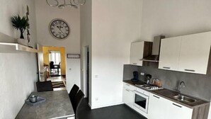 Une cuisine moderne avec des meubles blancs, un coin repas comprenant une table et des chaises, et une horloge au mur.