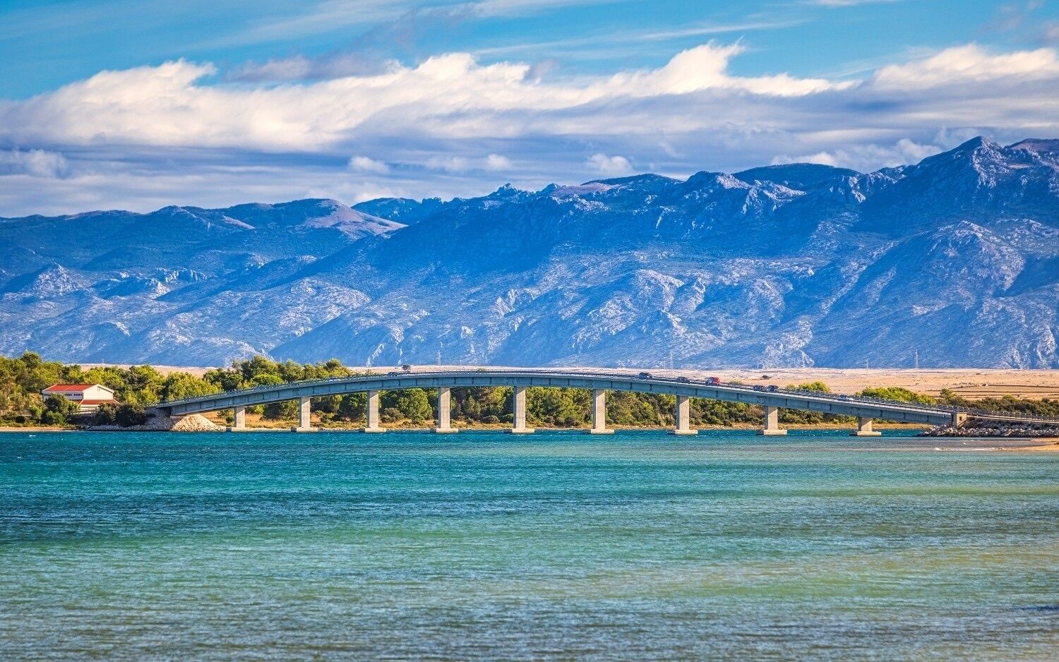 Un pont enjambant une étendue d’eau, avec des montagnes en arrière-plan.