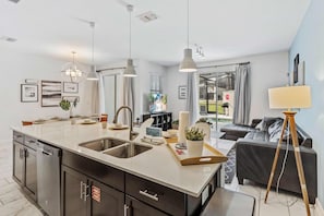 A modern kitchen with a central island, stainless steel appliances, and pendant lighting. - Townhome Oasis 4BR w Pool & Theme Room near Disney (Kissimmee)