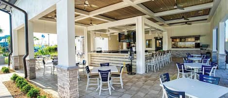 Un patio al aire libre con mesas y sillas, un área de bar y vistas del paisaje circundante.