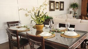 A dining area with a glass-top table, wooden chairs, and a white sofa in the background. - Family friendly condo located in Pineapple Village. (St Thomas)