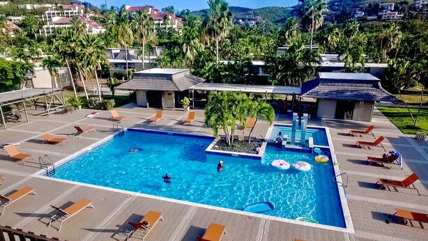 A large swimming pool with lounge chairs and palm trees. - Family friendly condo located in Pineapple Village. (St Thomas)