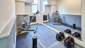 Un gimnasio con equipo de ejercicio, un espejo y mancuernas.