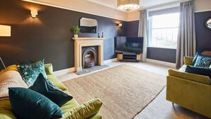 Una sala de estar con chimenea, televisión y dos sofás.