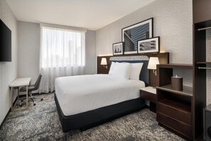 A hotel room with a large bed, a desk, a chair, and a TV. - DoubleTree by Hilton Long Island City, NY (Long Island City)