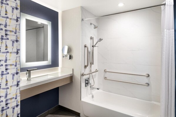 Une salle de bain moderne équipée d’une baignoire, d’une douche et d’un meuble-lavabo avec un miroir.