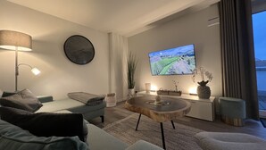 Un salon moderne avec un canapé, une table basse, un téléviseur et une lampe.