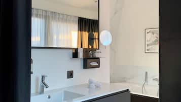 Un baño moderno con un espejo grande, un lavamanos y una ducha.