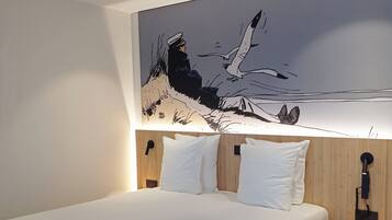 Una habitación de hotel moderna con una cama grande, ropa de cama blanca, un cabecero de madera y una obra de arte colgada en la pared que representa un paisaje marino.