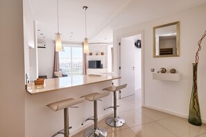 Un baño moderno con un espejo grande, dos taburetes, un tocador y un jarrón decorativo.