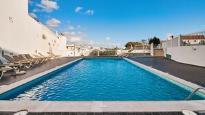 Ein Pool auf dem Dach mit Liegestühlen und freiem Blick auf die Skyline der Stadt.