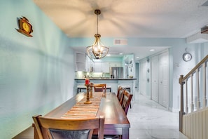 A dining area with a long wooden table, chairs, a hanging light fixture, and a kitchen in the background. - Community Pool & Boat Ramp! Inverness Home (Inverness)