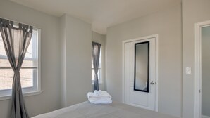 A hotel room with a large bed, a door with a mirror, and a window with curtains.