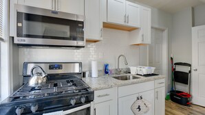 A modern kitchen with white cabinets, a stainless steel stove, a microwave, and a sink.