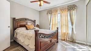 A bedroom with a wooden bed, a ceiling fan, and a window with curtains. - Close to San Antonio Zoo & Airport: Cozy Townhome (San Antonio)
