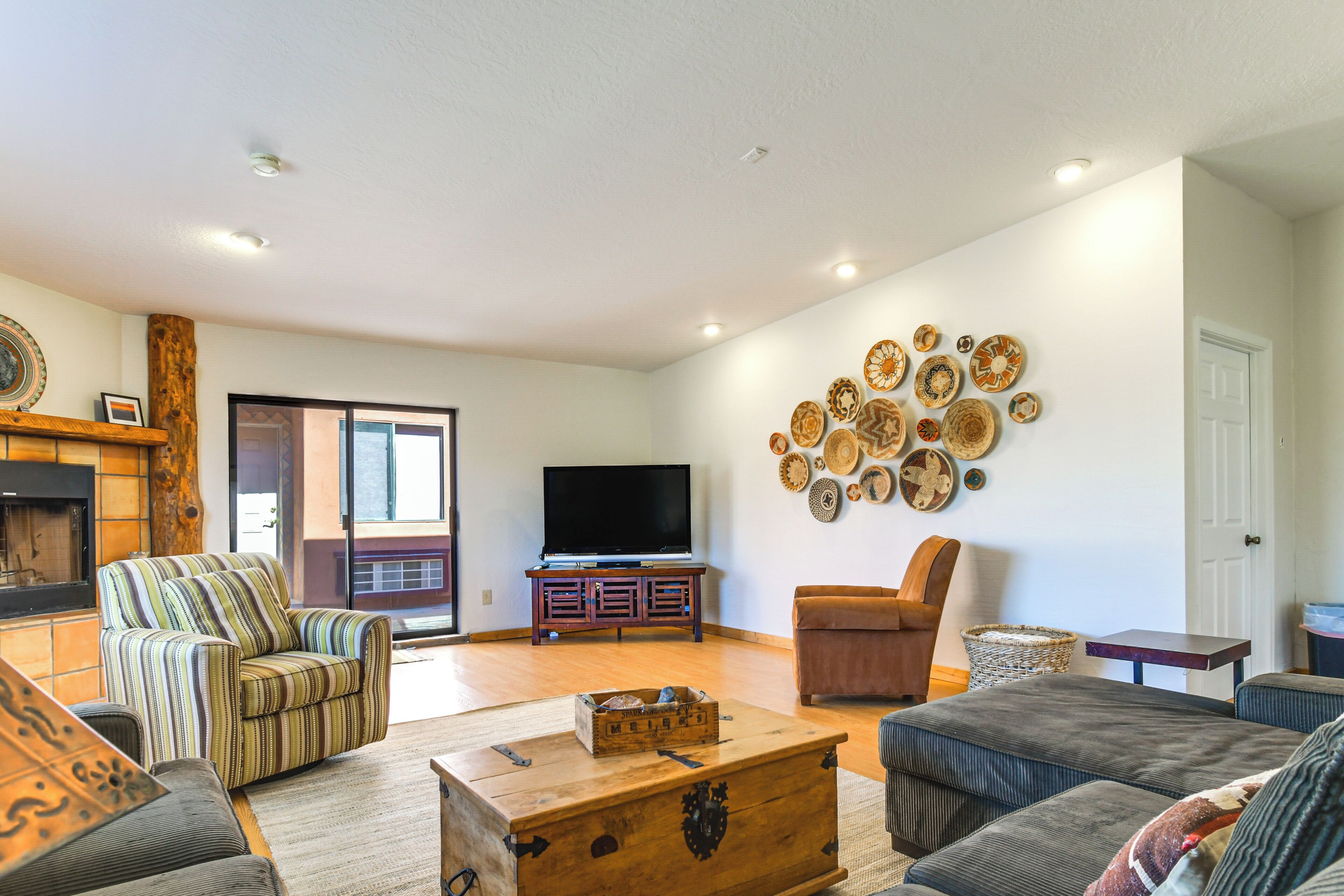 A living room with a television, striped armchair, brown armchair, and a wooden chest of drawers.