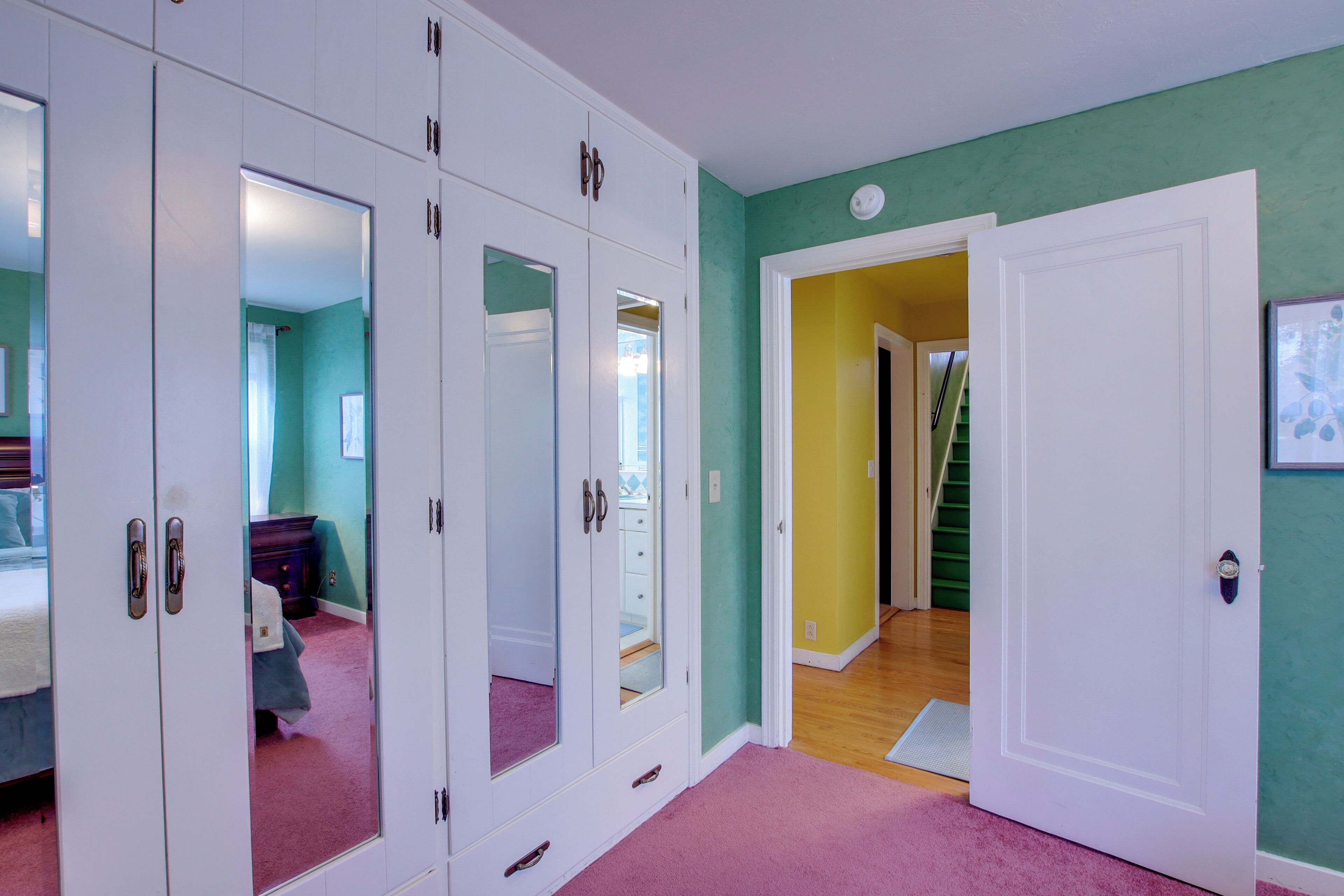 A bedroom with a bed, a wardrobe, and a mirror.