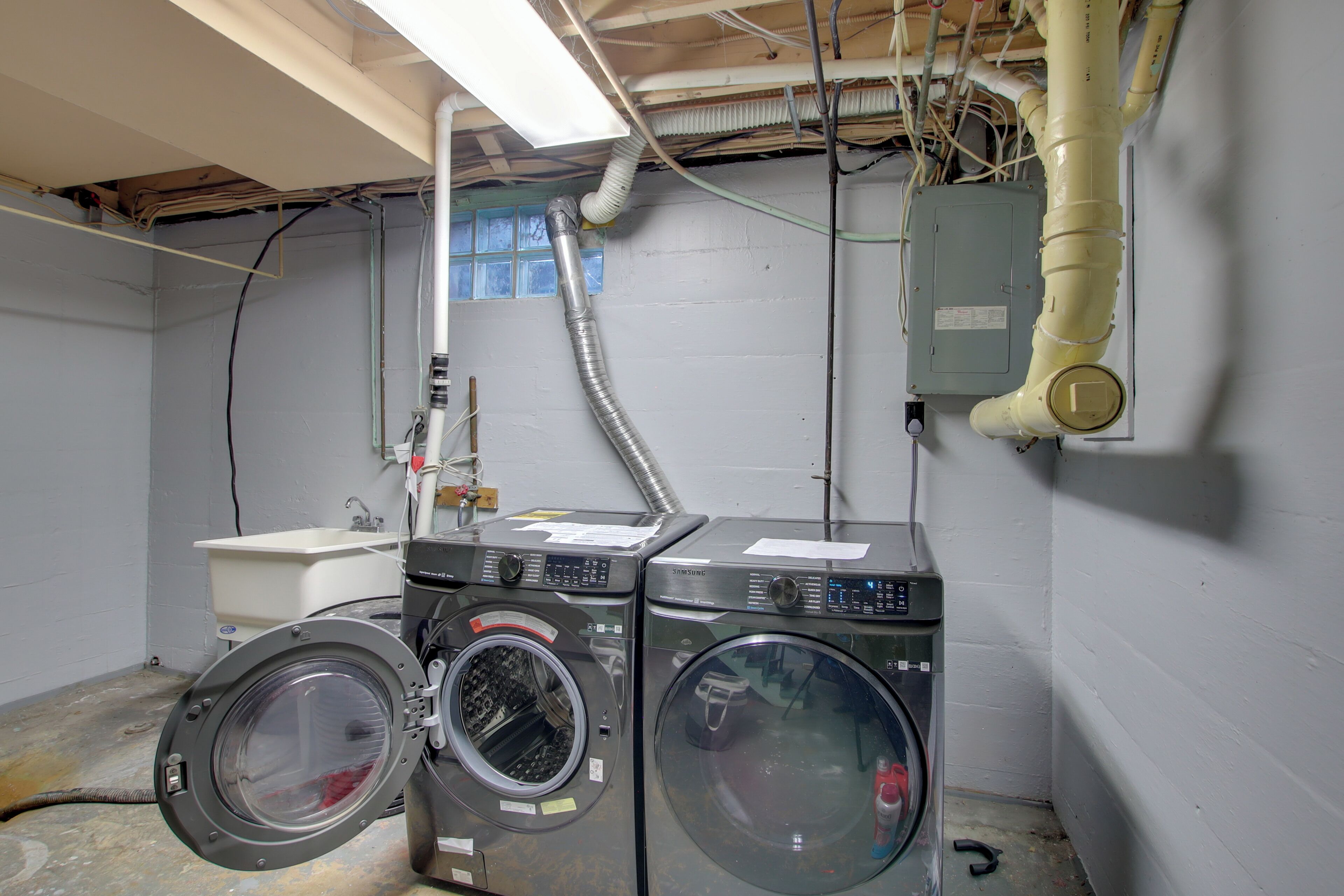 A laundry room with two washing machines, a sink, and a window.