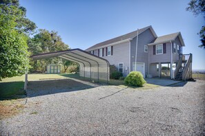 A two-story house with a covered patio area, a front garage, and a staircase leading to a deck. - Shiloh Vacation Rental w/ Albemarle Sound Views (Shiloh)