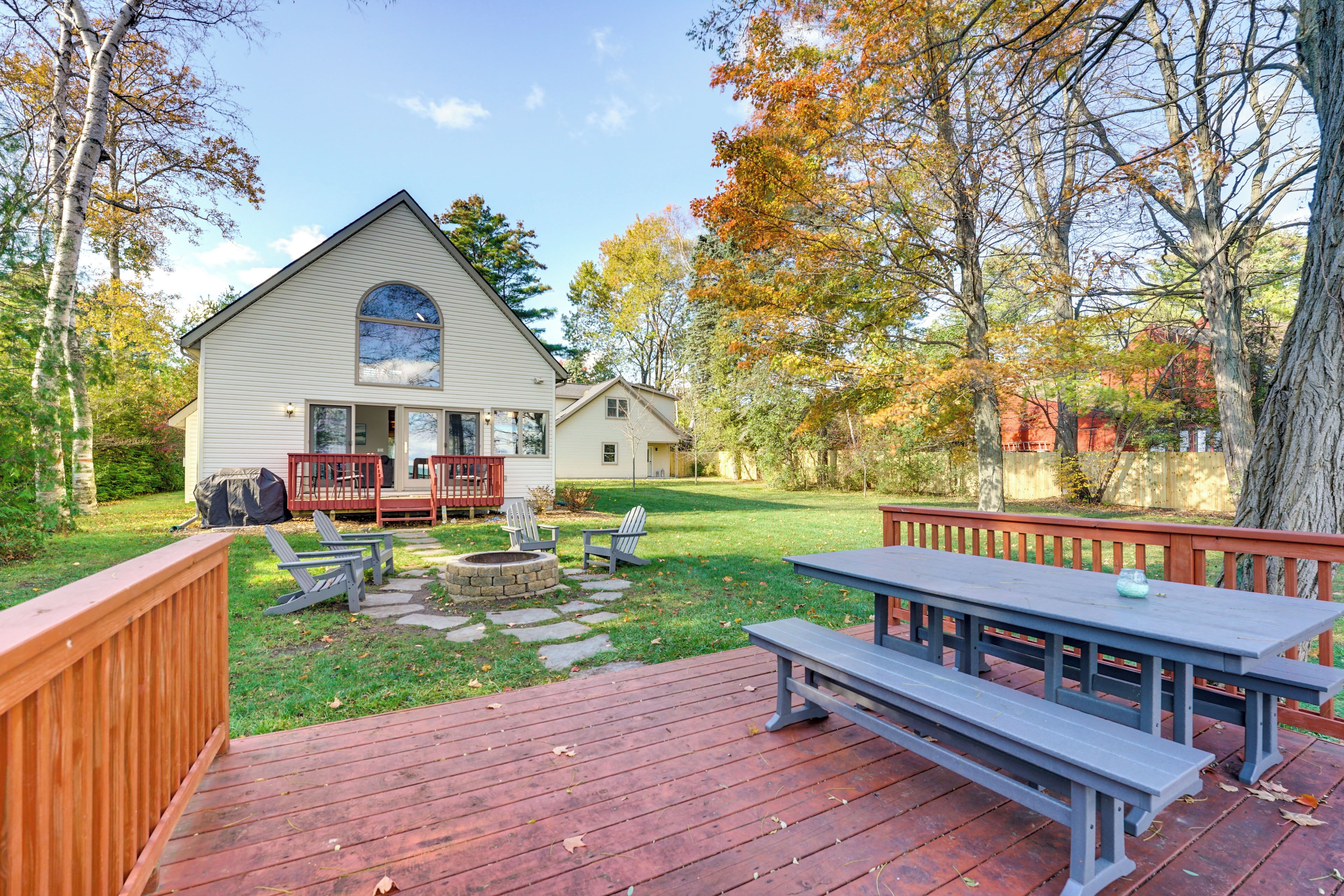 A house with a deck, a picnic table, and outdoor seating.