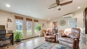 A spacious living room with a large leather recliner, a dining area, and a kitchen in the background.