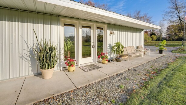 A single-story building with a covered patio area, potted plants, and outdoor seating.