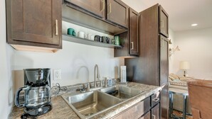A kitchen with dark wooden cabinets, a granite countertop, a coffee maker, and a sink.