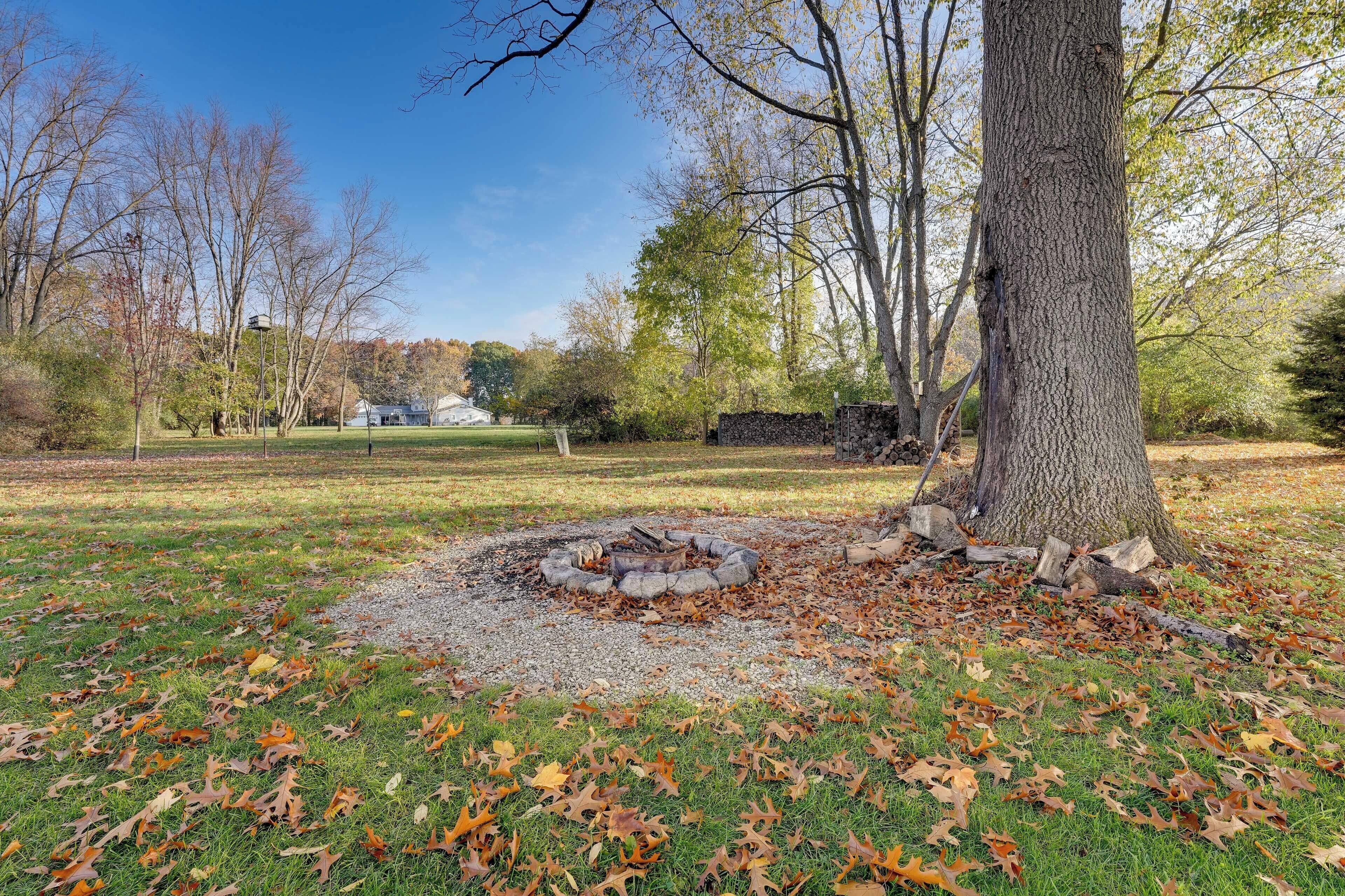 Een park met een vuurplaats, bomen en een stenen muur.