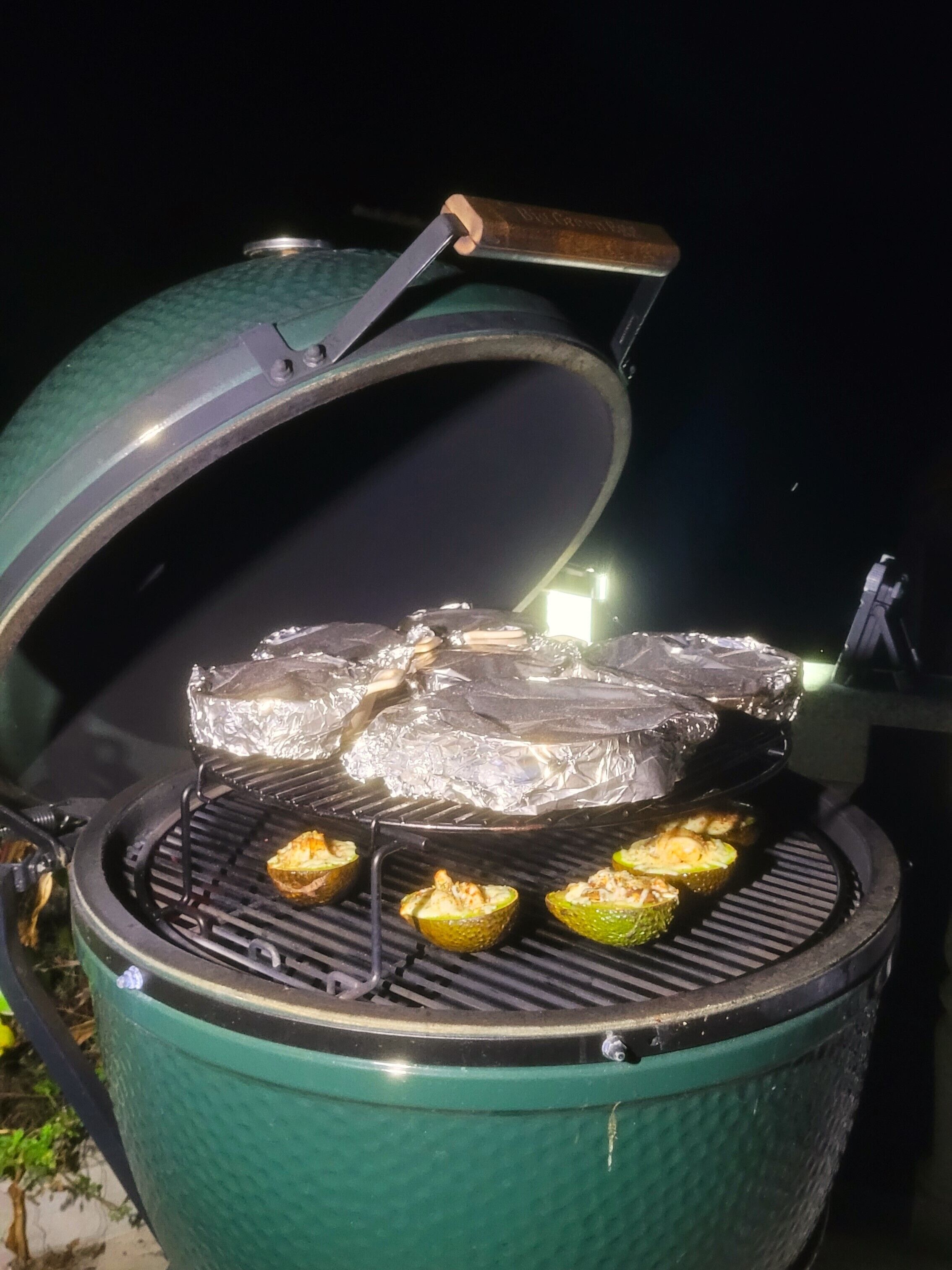 A portable grill with a lid open, cooking food on the grill.