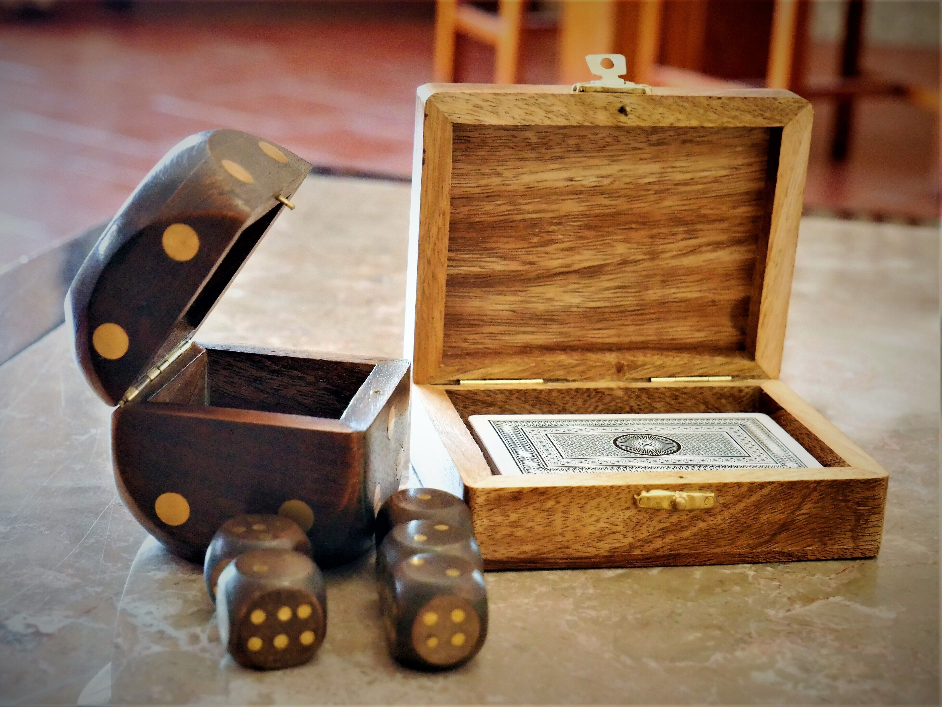 A wooden box with a hinged lid, containing a playing card and dice.