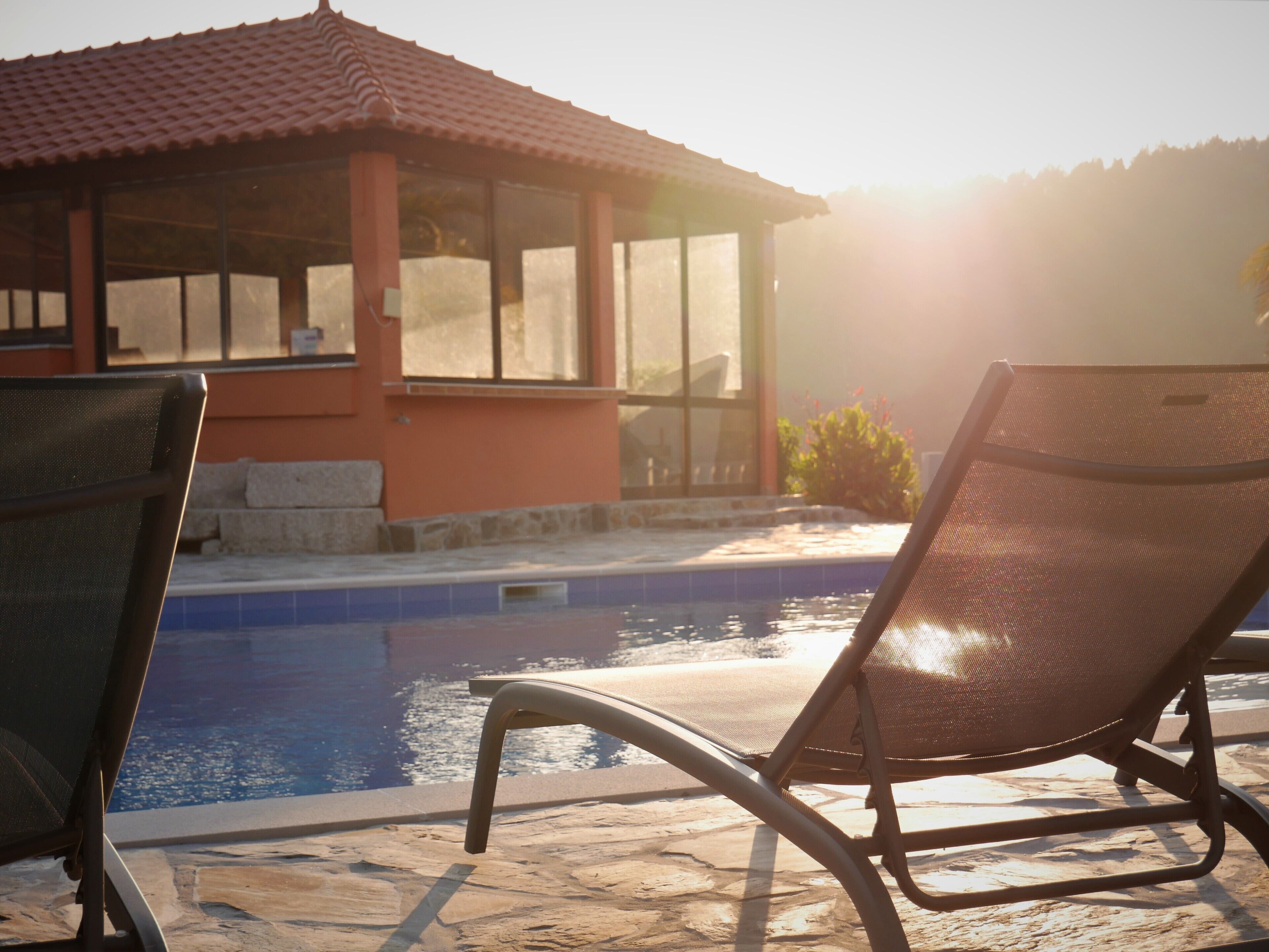 A poolside area with lounge chairs and a building with large windows.