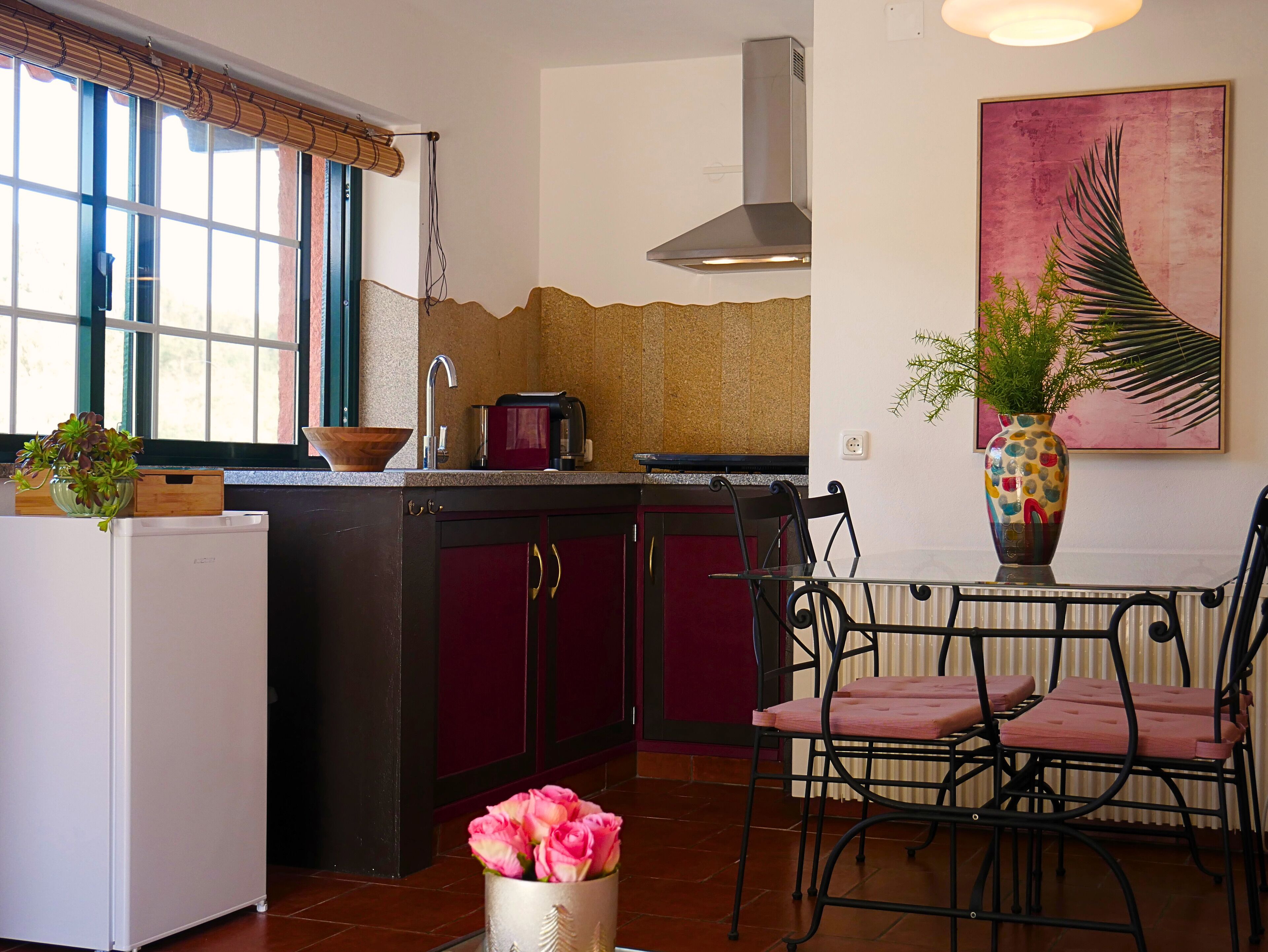 A kitchen with a refrigerator, a sink, a stove, and a dining area with chairs and a table.