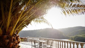 A terrace with a table and chairs overlooking a body of water and a forested hillside. - Encontro no Rio (Tábua)