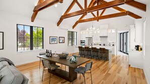 Una cocina amplia con armarios blancos, una isla central y un comedor con mesa y sillas de madera.