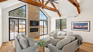 Un salón amplio con techo alto, ventanas grandes y chimenea.